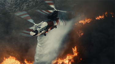 Un avion de Coulson Aviation volant au-dessus d’un feu de forêt qui fait rage au sol.