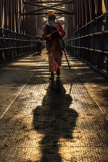 Indian man walking across steel bridge