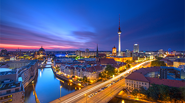 Berlin skyline panorama showing the TV Tower at Alexanderplatz, cathedral and traffic against a blue purple sunset
