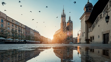 The sun rises over an empty market square surrounded by old buildings.