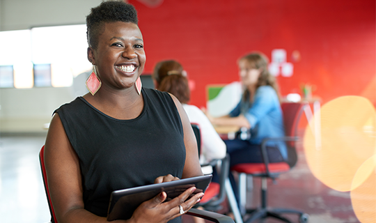 Femme noire entrepreneuse confiante travaillant sur une tablette dans un espace de bureau