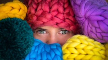 Une entrepreneure observe de derrière ses stocks de laine colorée.