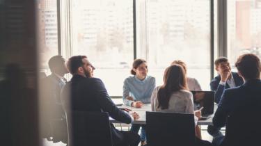 Employees collaborating at a board room table to be more competitive globally