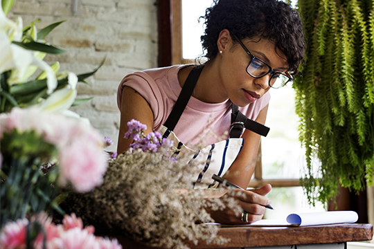 Une femme noire ecrit des notes dans un magasin de fleurs