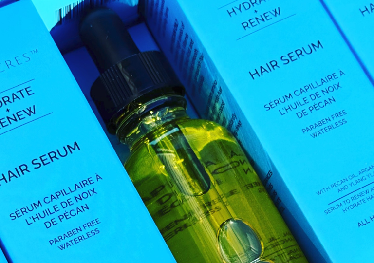 A bottle of Nuez Acres hair serum is displayed beside light blue boxes of the product. Nuez Acres expanded to the Indo-Pacific after attending a Team Canada Trade Mission.