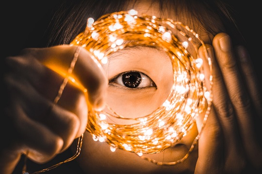 Close-up of an eye in the centre of a strand of mini lights.