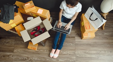 woman on laptop surrounded by shipping boxes