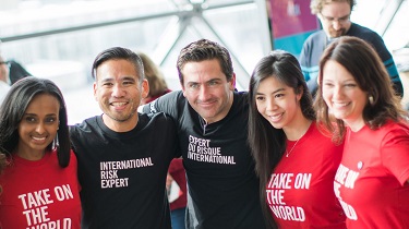 Diverse EDC employees wearing shirts that say “Take on the World” and “International Risk Expert”
