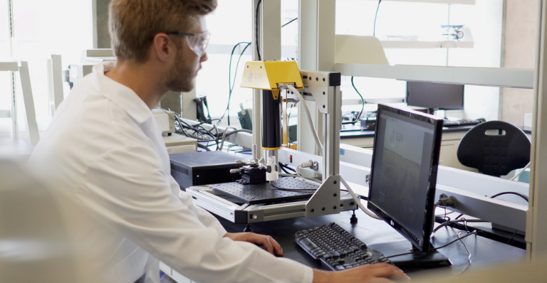 Scientist looking at computer screen in lab environment.