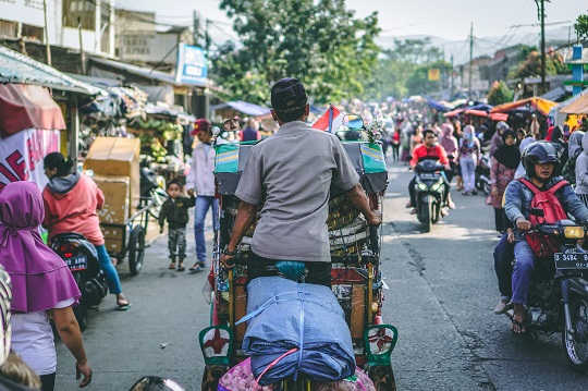 Motorcyclists navigate street lined with vendors