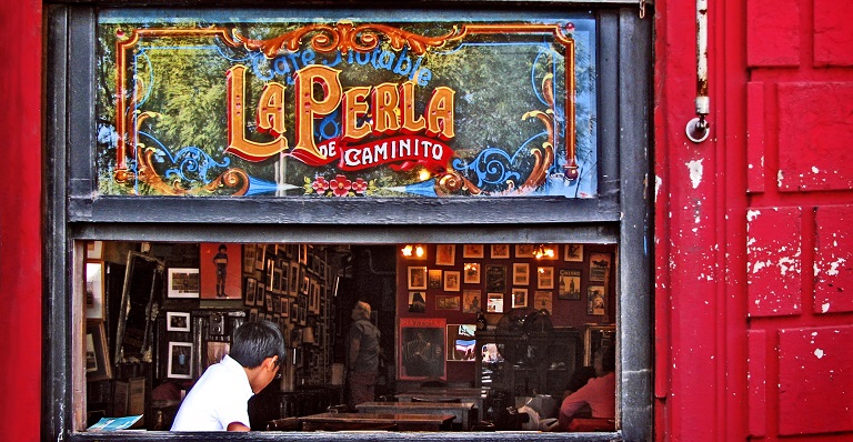 Homme assis à la fenêtre de La Perla de Caminito, célèbre café de Buenos Aires, qui a vu jour en 1882.