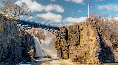 Bridge spanning rushing water with U.S. flag flapping in the wind