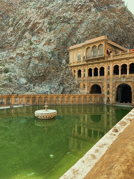 Indian temple with green pond in front of it