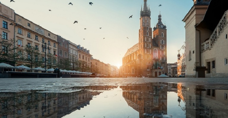 Le soleil se lève sur une place de marché vide et entourée de vieux bâtiments.