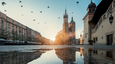 Le soleil se lève sur une place de marché vide et entourée de vieux bâtiments.