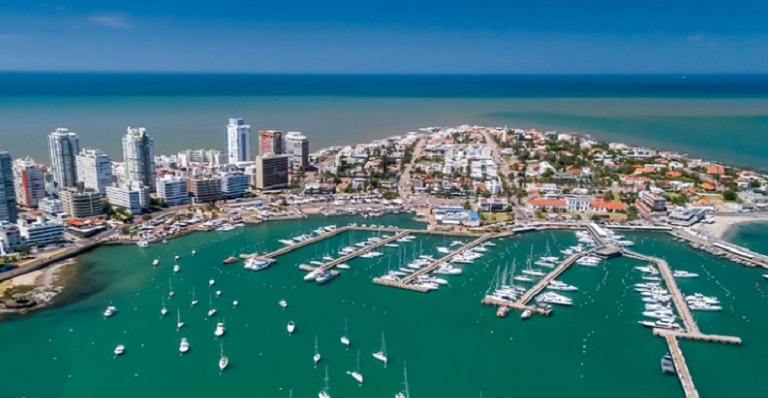 A port city with several sky scrapers and a busy boating area is seen from high above.