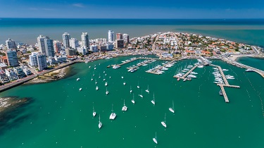 Vue aérienne des gratte-ciel et de la zone de navigation achalandée d’une ville portuaire.