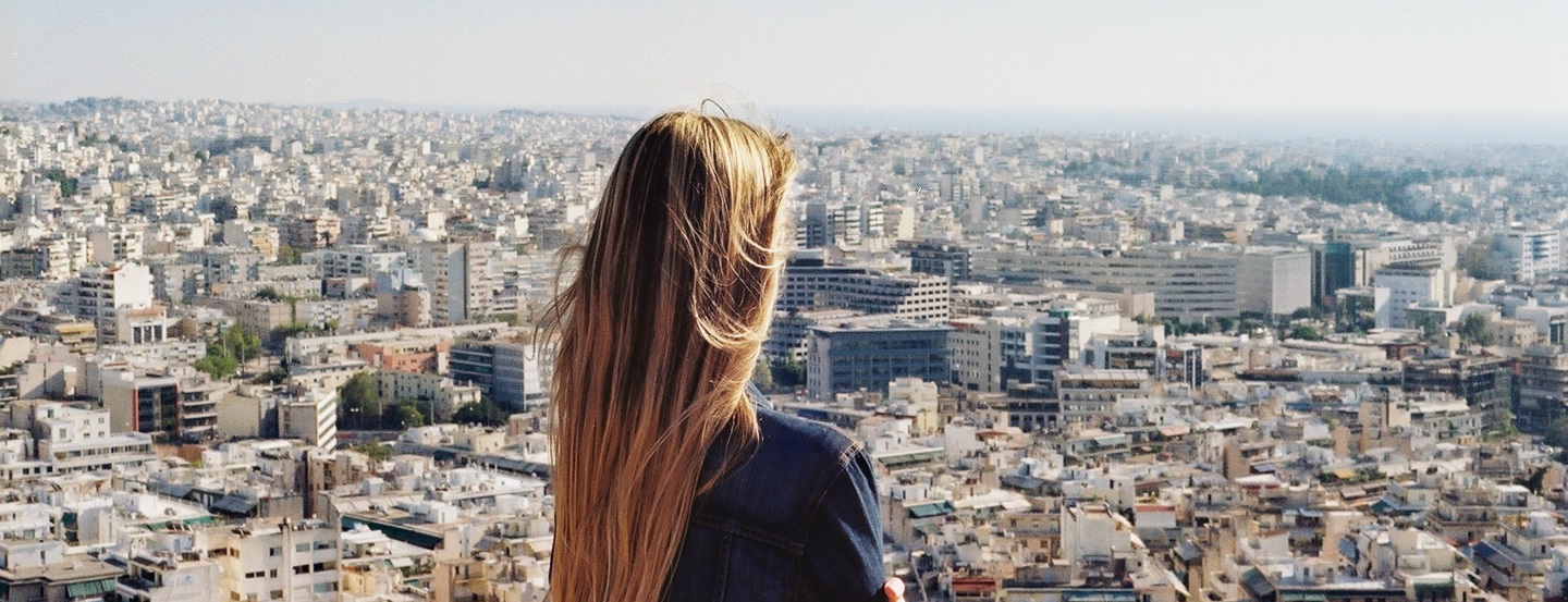 Une entrepreneure regardant l’horizon, au-dessus des toits d’une grande ville.