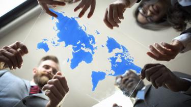 Business colleagues gather around world map image etched on glass.
