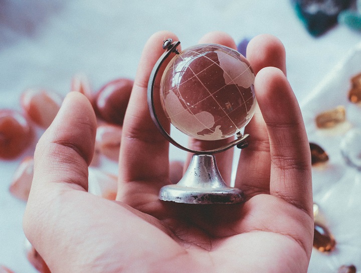 Crystal globe rests in the palm of a man’s hand.