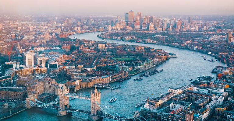 Aerial view of London, England, featuring buildings, residential areas, a river and a bridge.