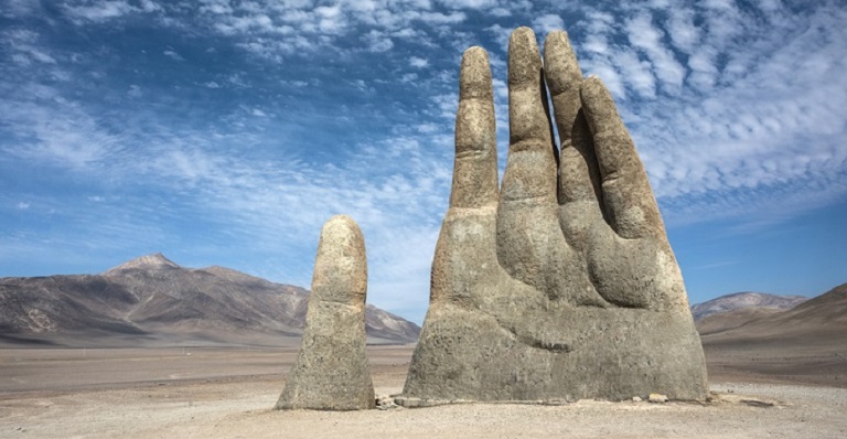 A famous Chilean sculpture of a giant hand reaching out of the sand. 
