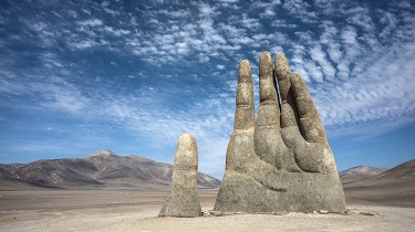 A famous Chilean sculpture of a giant hand reaching out of the sand.