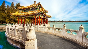 A colourful Asian pagoda sits at the edge of a lake.
