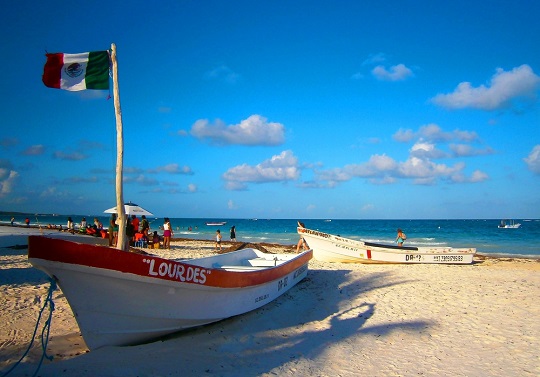 Mexican flag, boats and tourists on famous Playa Paraiso Beach.