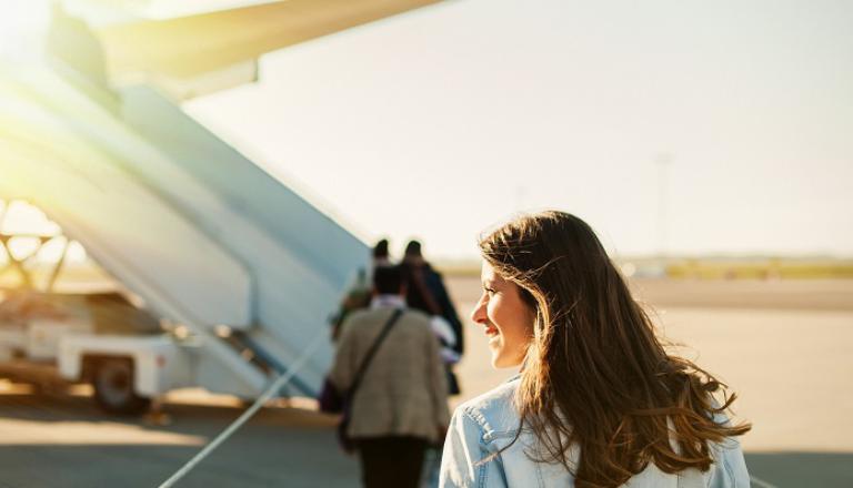 Radiant female exporter walks across tarmac to board plane.