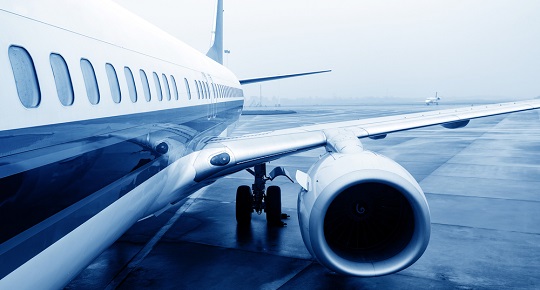 An airplane sits on a slightly foggy tarmac.