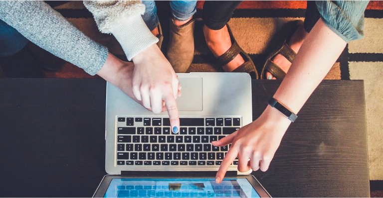 Three entrepreneurs gather excitedly around a laptop to see their new online store.