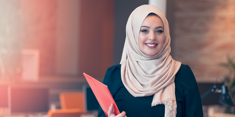 Une femme d’affaires portant le hijab tient des dossiers dans un bureau.