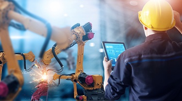 Engineer checks robotic arms in auto factory.