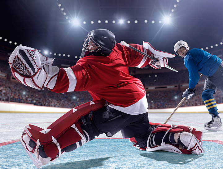 Un gardien de but de hockey s'étire pour arrêter un tir lors d'un match sur une patinoire.