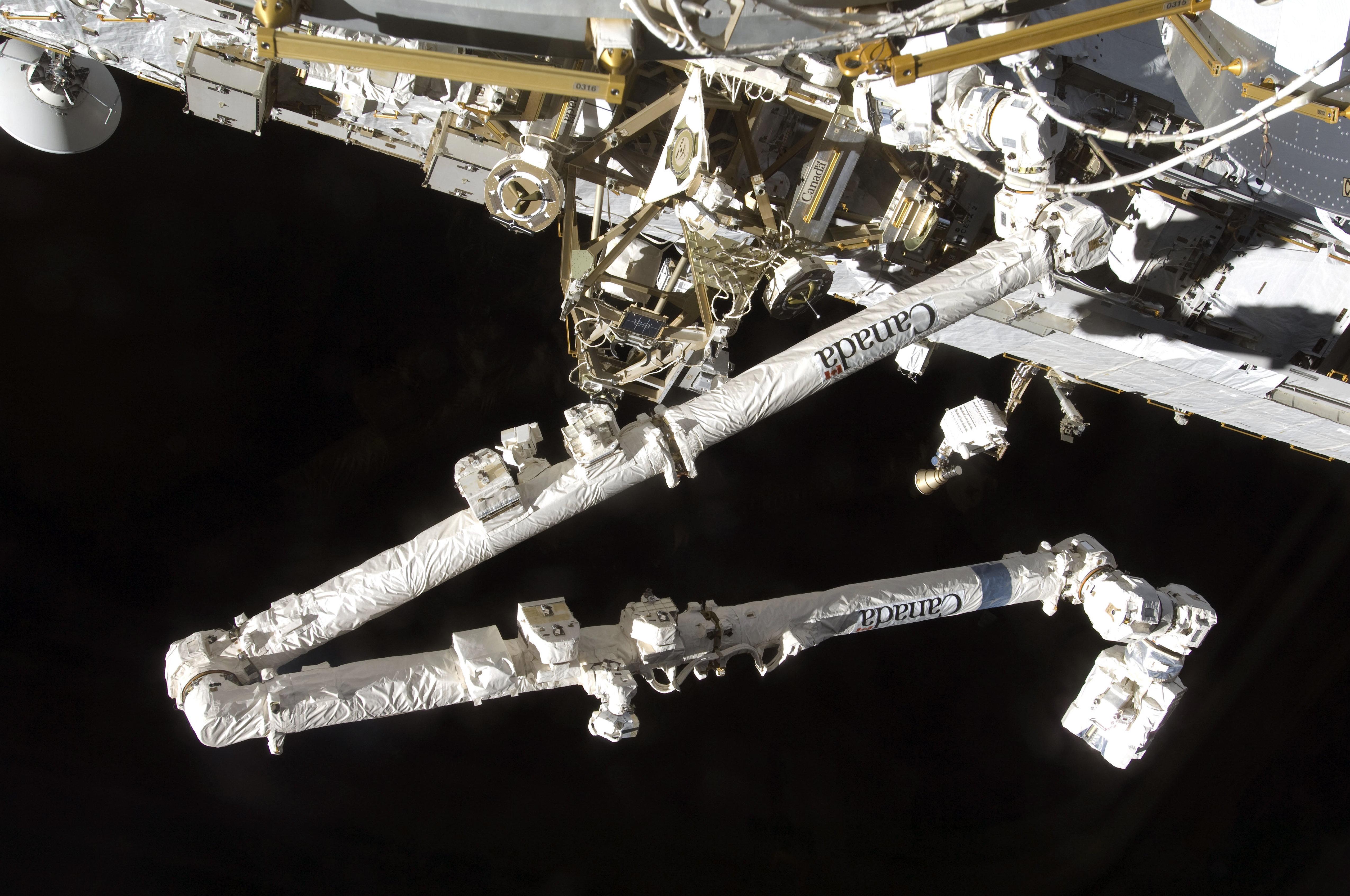 Le système de manipulateur à distance de la station spatiale de fabrication canadienne (Canadarm3) se détache sur la noirceur de l'espace depuis la station spatiale.