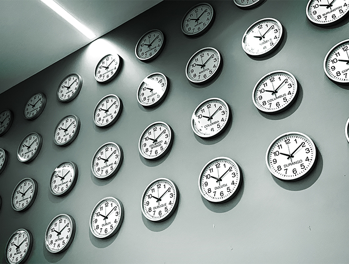 Un mur recouvert d'horloges analogiques indiquant des heures différentes.