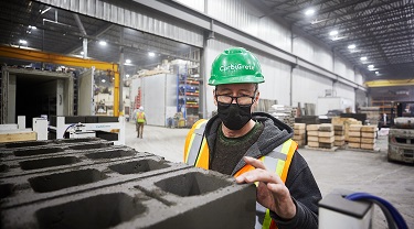 Worker in a manufacturing facility in Quebec tests strength of cement-free concrete blocks.