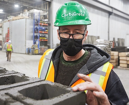 Un travailleur dans une usine du Québec teste la force de blocs de béton sans ciment.