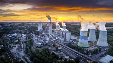 Une usine crache de la fumée sur fond de soleil couchant spectaculaire.