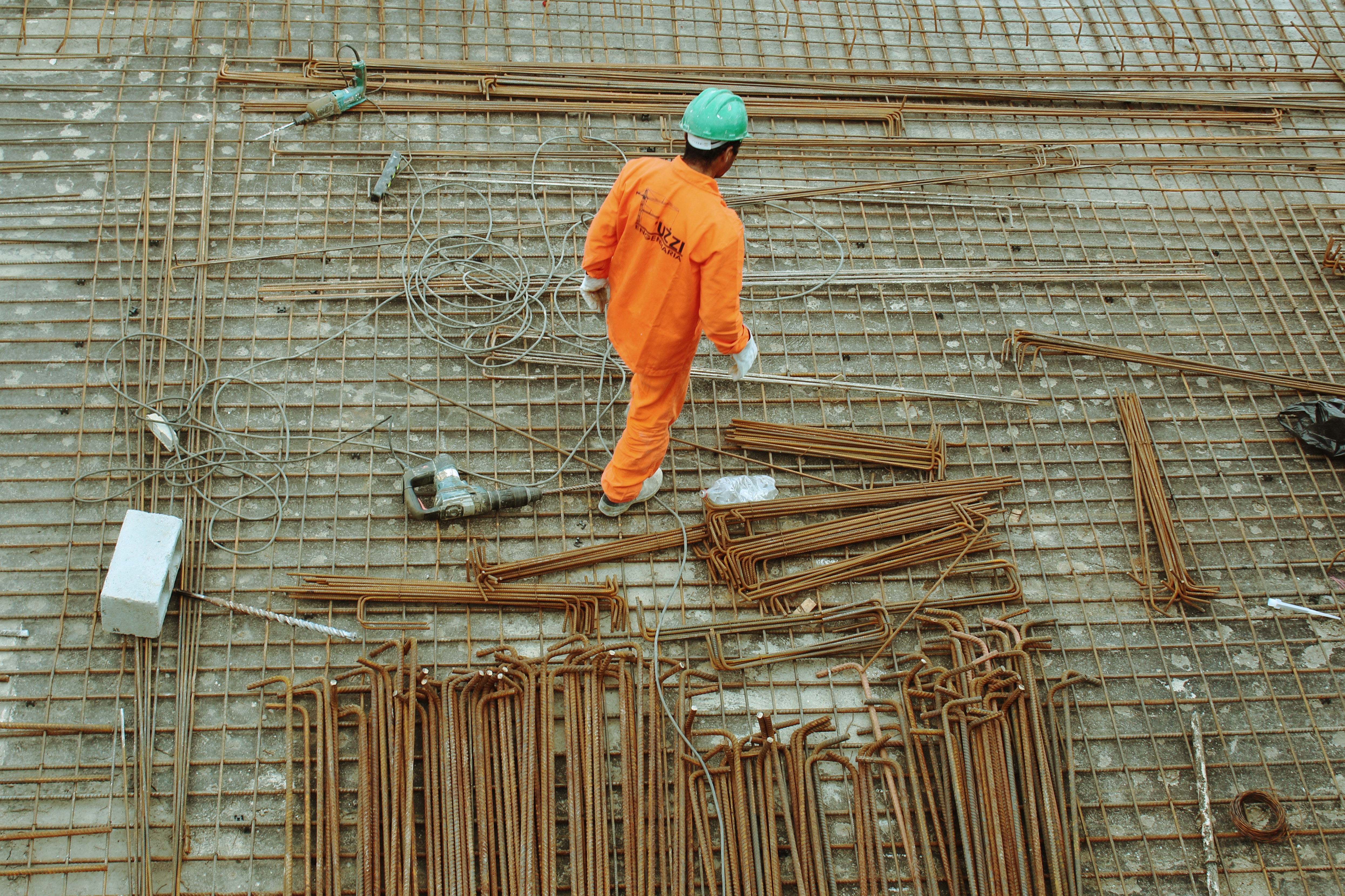 Construction worker walks past steel rods on building site.