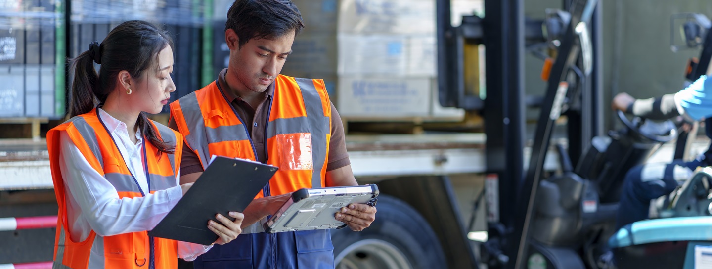 Les employés d'entrepôt vérifient les documents pendant que le chariot élévateur charge l'expédition dans un camion.