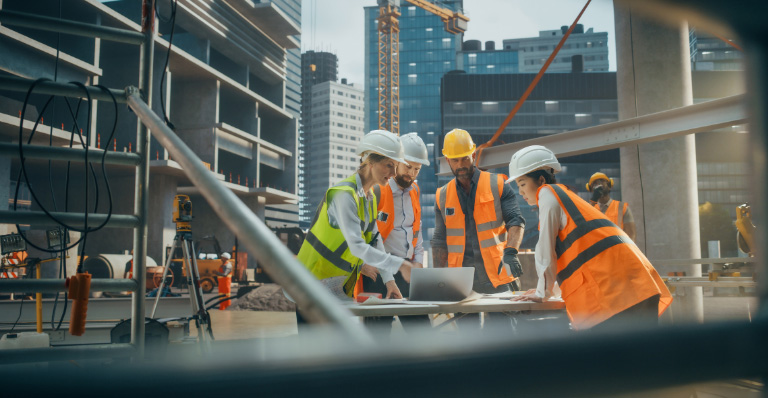 Ingénieure civile avec ordinateur portable parlant à des ouvriers sur un chantier de construction résidentielle.