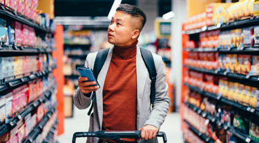 Handsome Asian man searches for groceries from list on his phone.