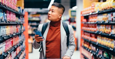 Handsome Asian man searches for groceries from list on his phone.