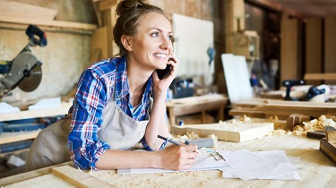 Une charpentière parle avec son client tout en prenant des notes dans son atelier