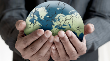 Gros plan sur les mains d’un homme tenant un globe terrestre fissuré