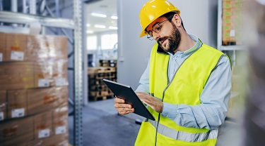 A warehouse supervisor checks his inventory on his tablet.