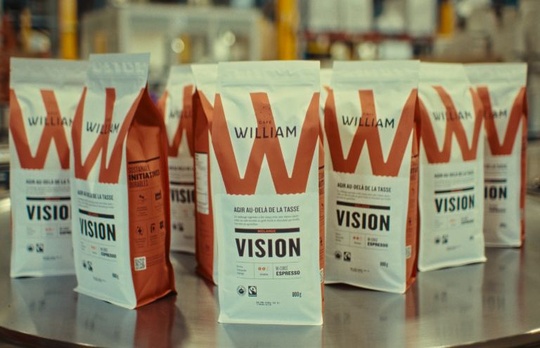 Café William Vision coffee bags displayed on a metal table in a production facility.