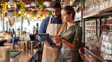 Worried restaurant owner checks business documents while standing behind counter